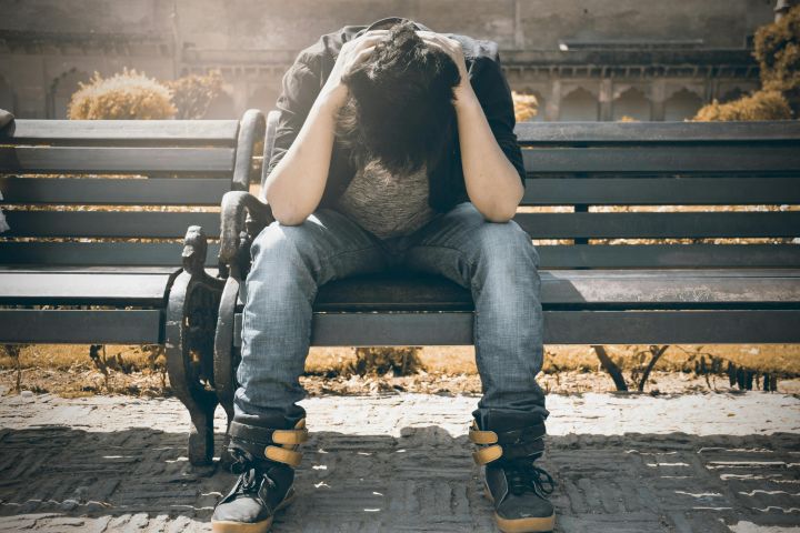 Man sitting alone on a bench in Agra, displaying signs of stress and loneliness.